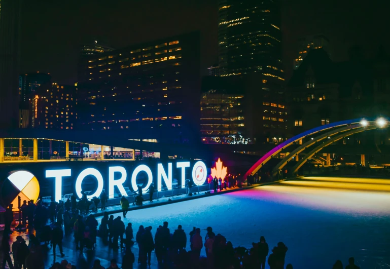 a night s of people standing outside a large white light tunnel and the toronto sign