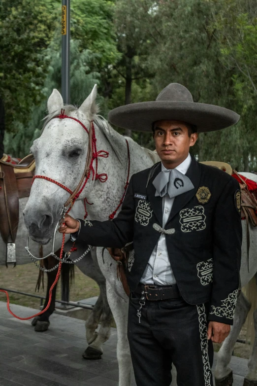 a man in a mexican gaucho next to a horse