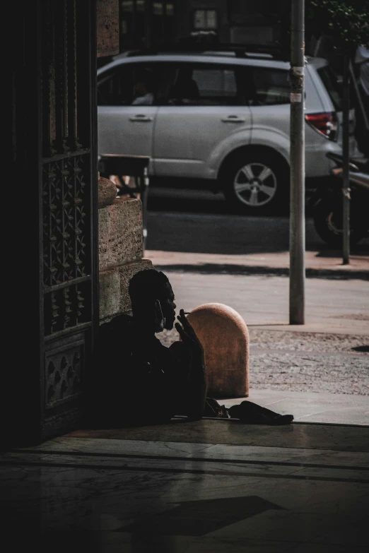 a person sits on a bench next to a parked car