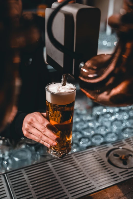 someone making a beverage at a restaurant while another bartender is pouring a drink