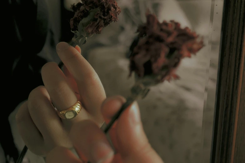 a woman holding a flower with her wedding band on