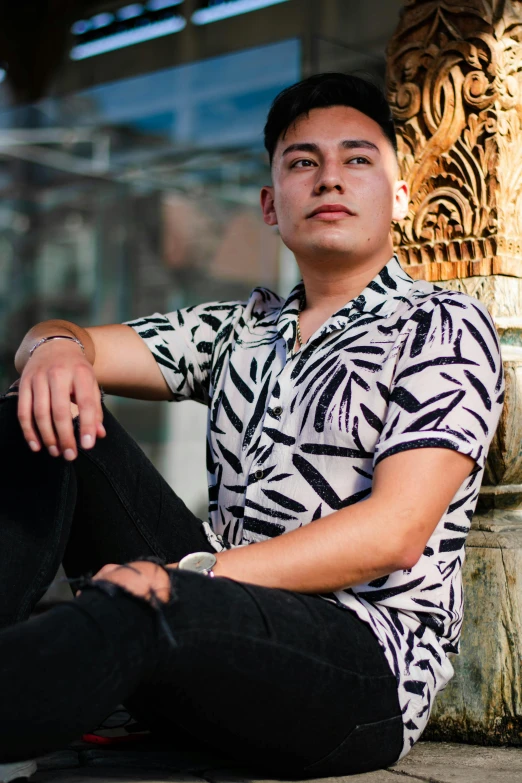 a man is wearing a ze shirt while sitting on a ledge