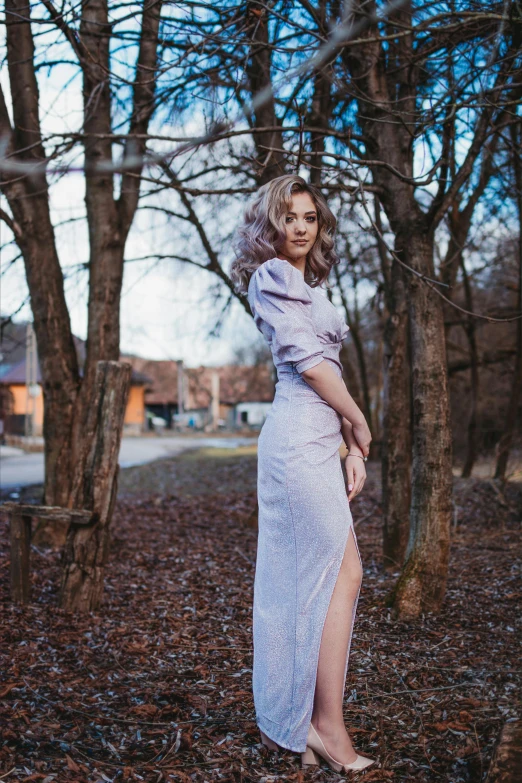 woman in purple dress standing in leaves in the woods