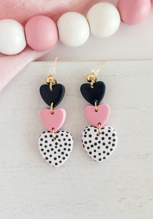 a pair of heart - shaped earrings hanging on a chain