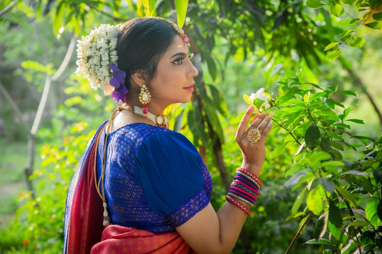 a woman in traditional garb and head jewelry holding flowers