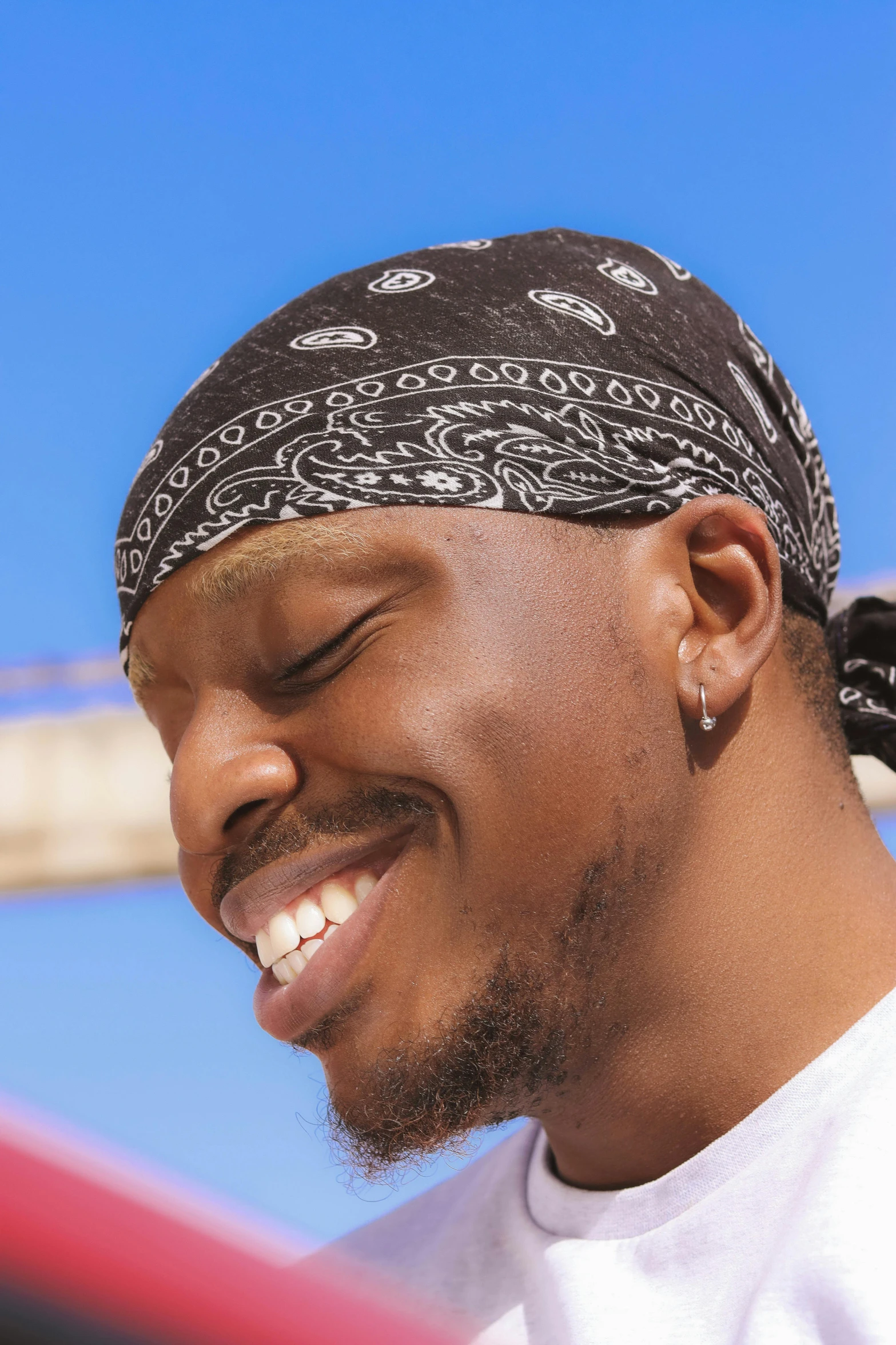 a black man wearing a bandana and looking at his cell phone