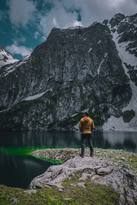 a man standing on the edge of a cliff looking over a lake