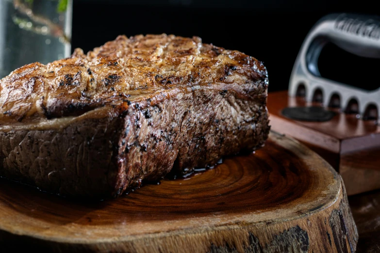 a steak on a wooden stump beside a black iron grate