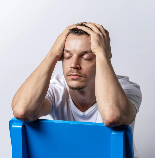 a young man has his head propped up on a blue chair