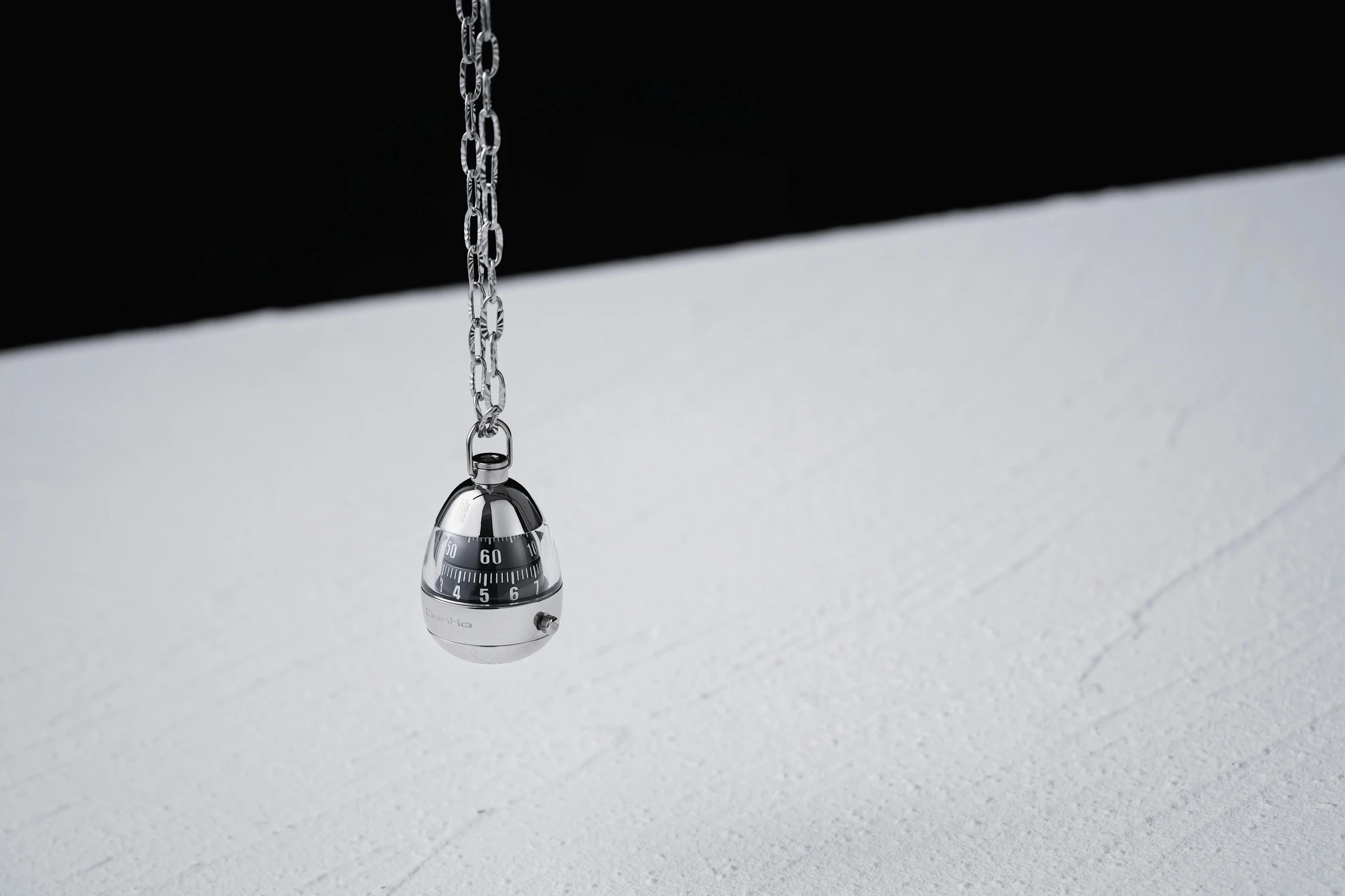 a small silver birdcage hanging from a long chain