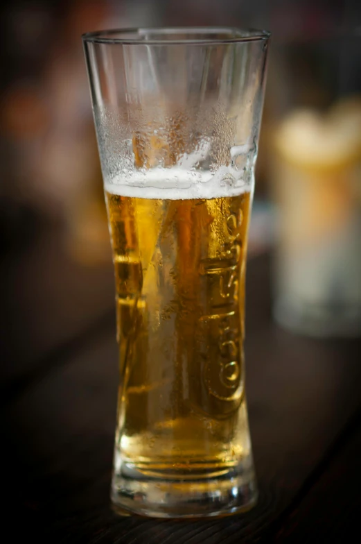 a glass full of beer sitting on top of a wooden table