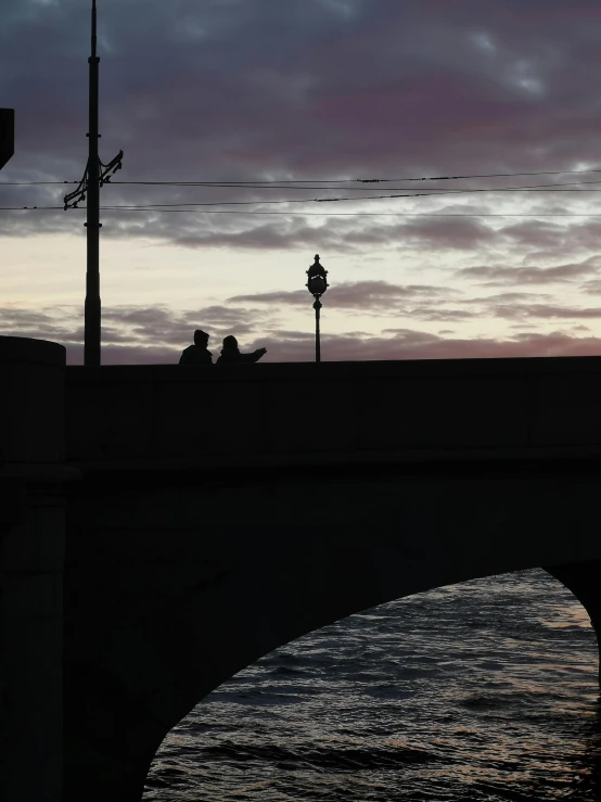 silhouette of a bridge with two people sitting on top