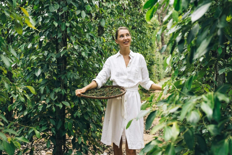 a woman in white shirt and shorts holding a basket of fruit