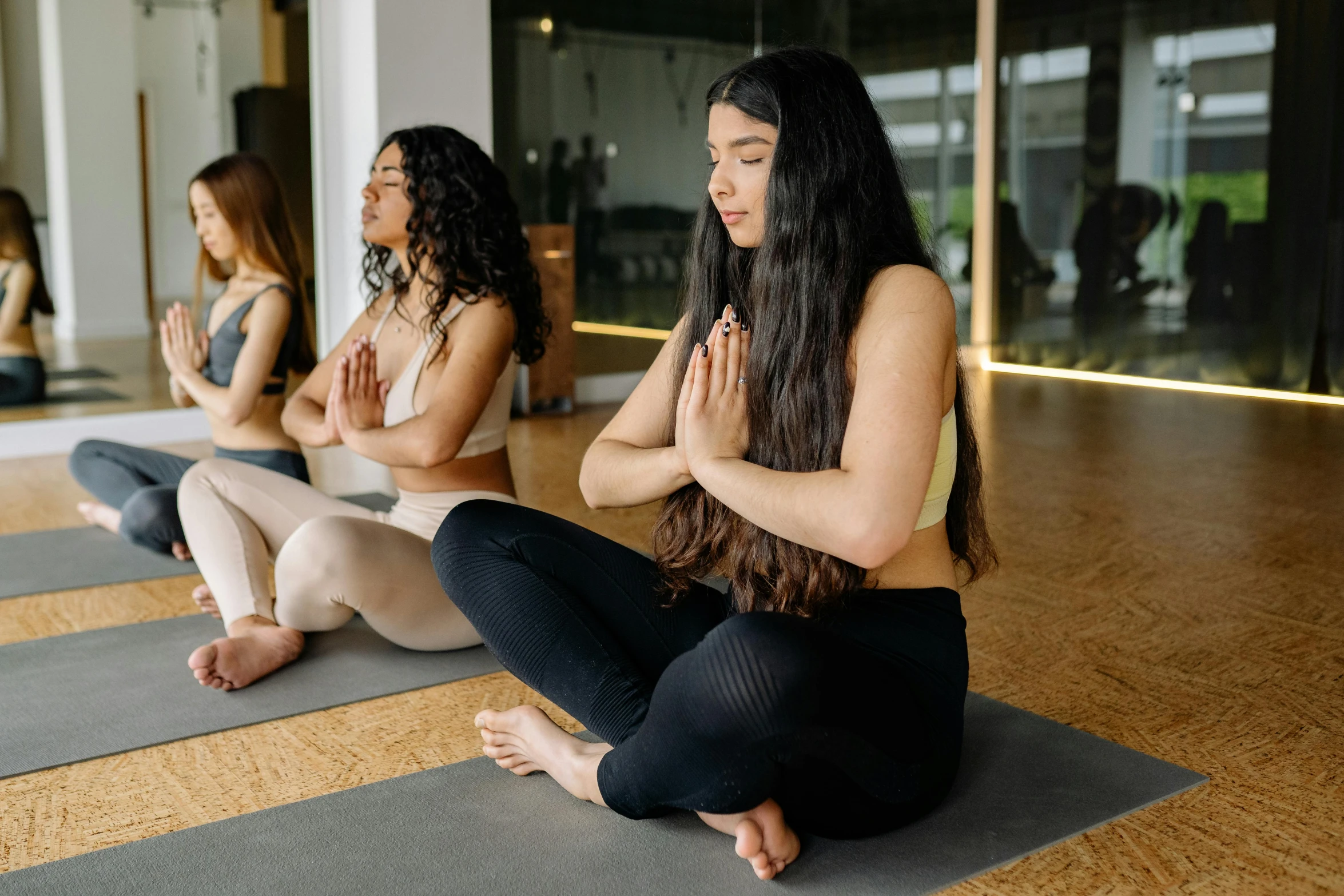 three women sitting in a yoga pose on their own