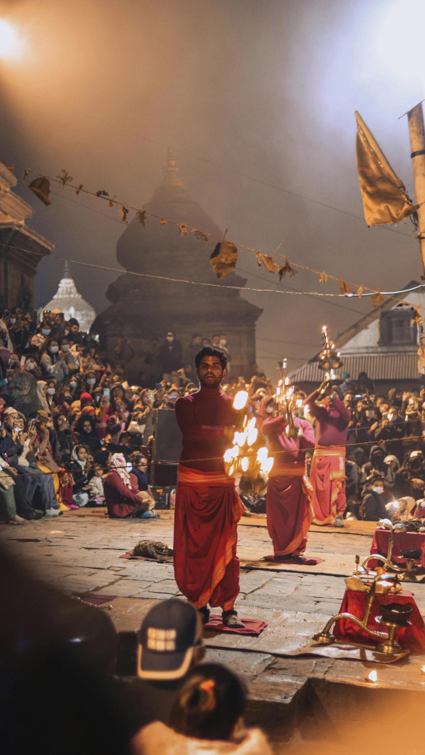 a group of people with torches and red robes performing in front of a crowd