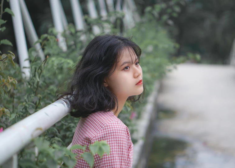  wearing pink shirt standing on sidewalk next to tall grass