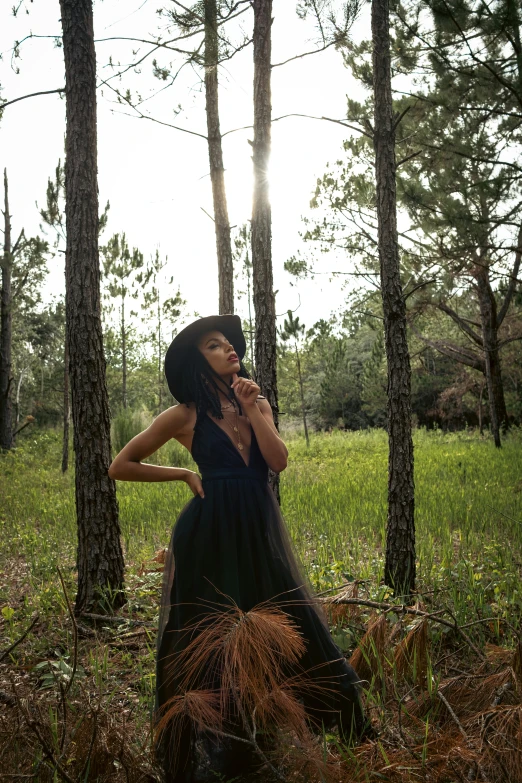 a woman in a black dress sitting on top of a tree trunk