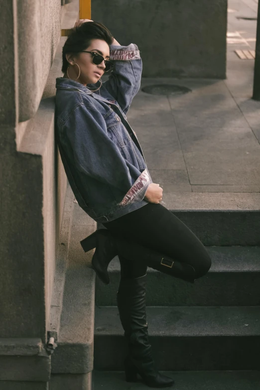 a woman in black boots leaning on some steps