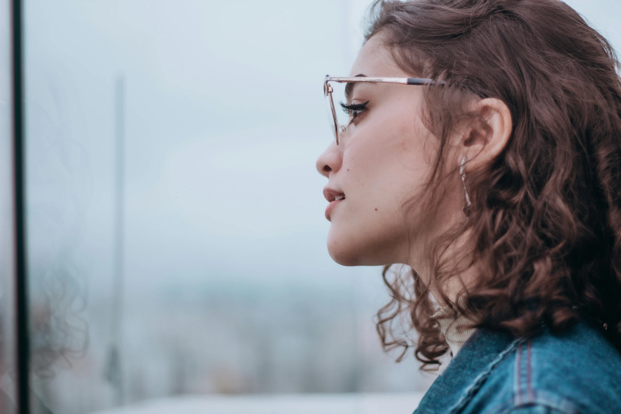 a woman wearing glasses looking out the window