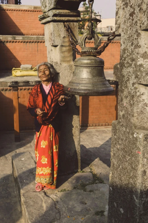 a woman leaning on a pillar with a bell