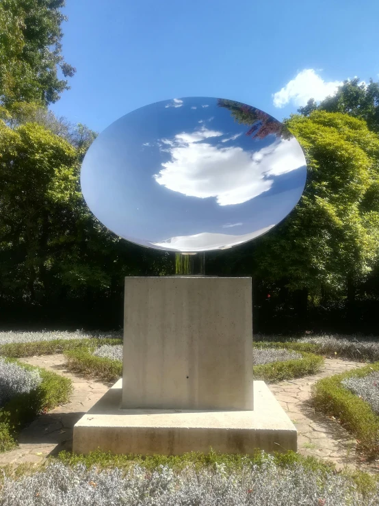 large round mirror over sculpture sitting in grass