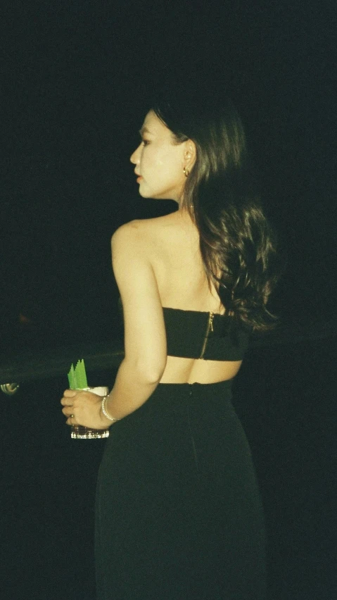 a beautiful young woman in a black dress holding a glass