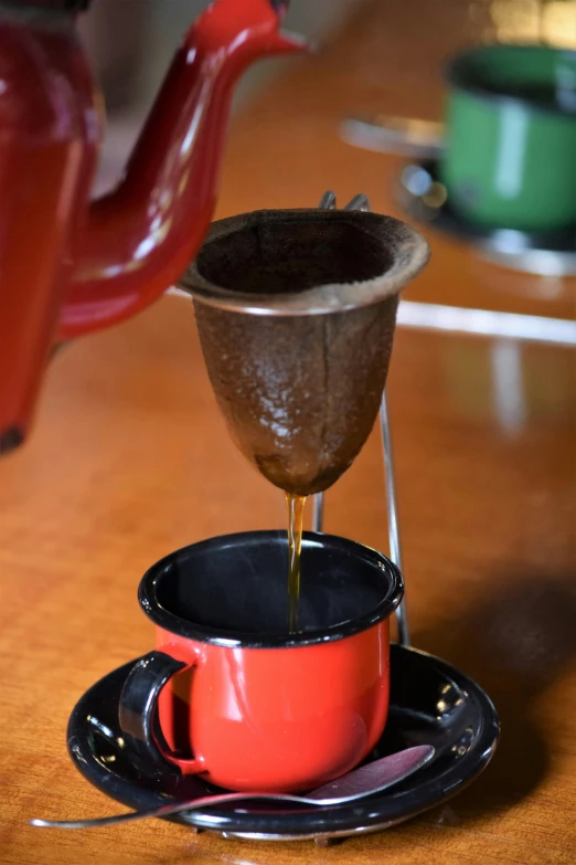 a driper being poured over coffee mugs on a table