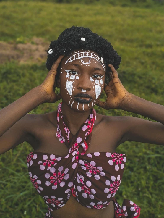 a young woman with white face paint holding her hands to her head