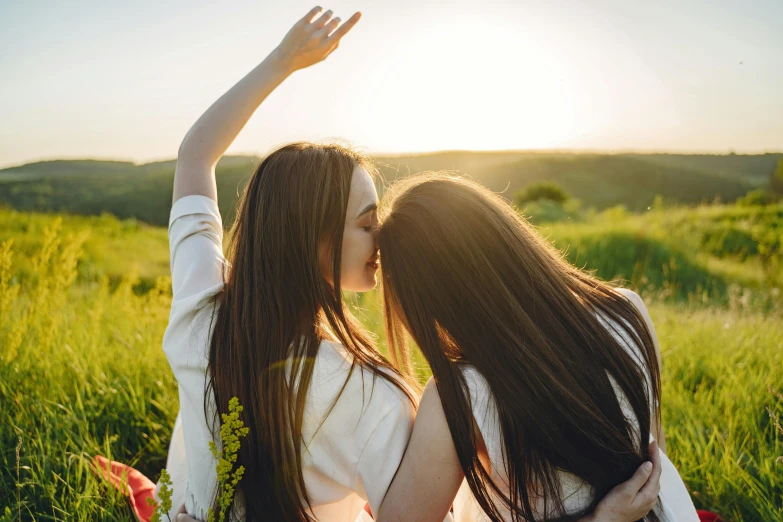 two women sitting in grass with their heads bowed