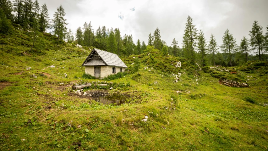 a small hut sits on the side of a hill