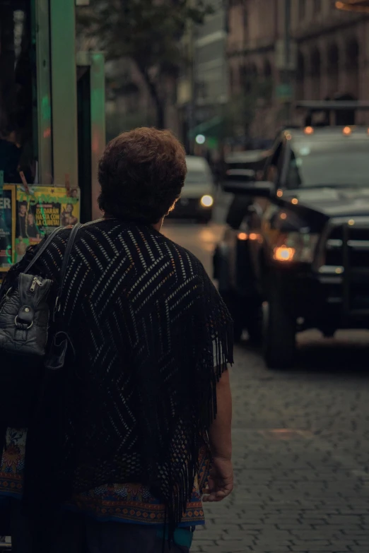 a lady with an umbrella on the sidewalk of a busy street