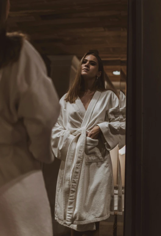 a person wearing a robe standing by a mirror
