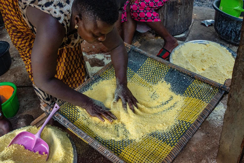 a woman is preparing some food outdoors on the ground