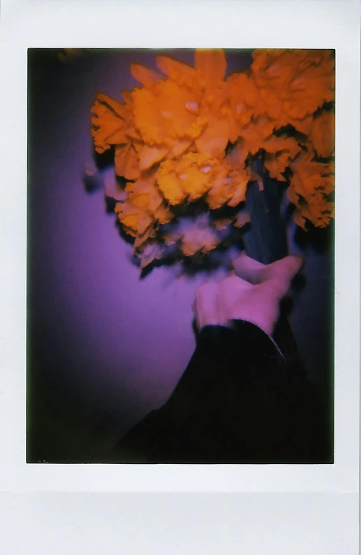 a polaroid po of a person's face holding a bouquet of flowers