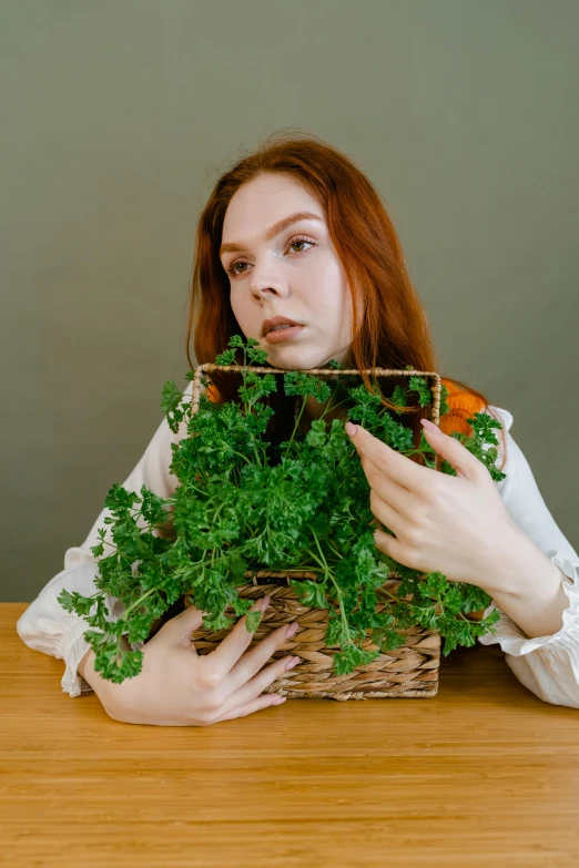 the young lady is holding a basket of green vegetables