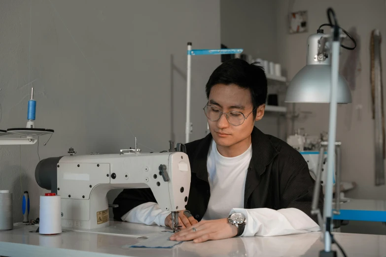 a man in a glasses sews on an over head machine