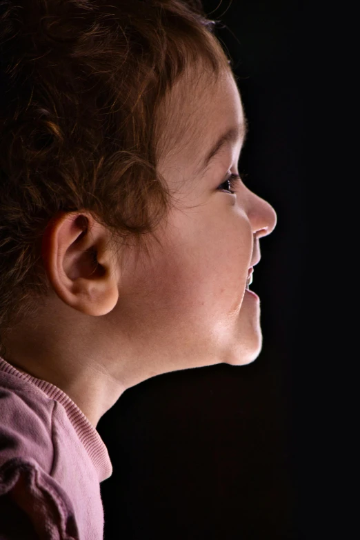 a smiling child with light brown hair looking away