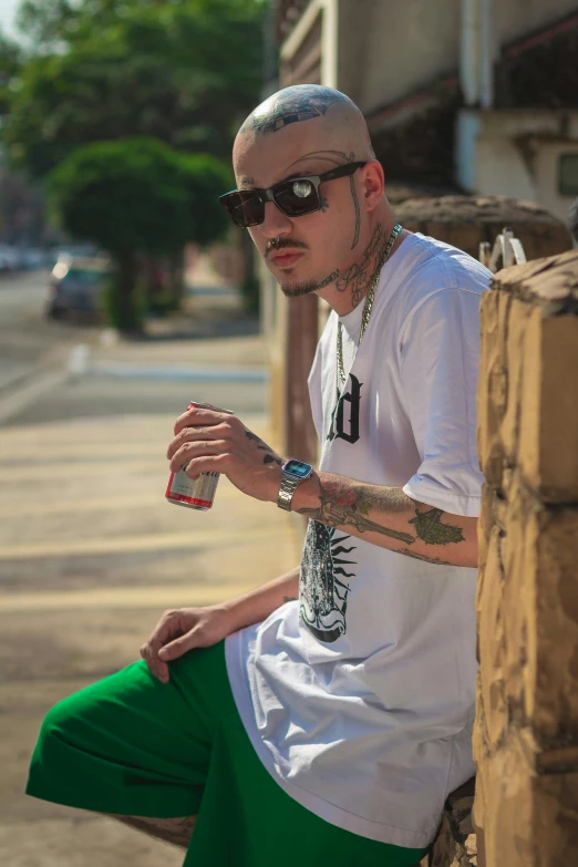 a man with tattooed arms sits on the side walk