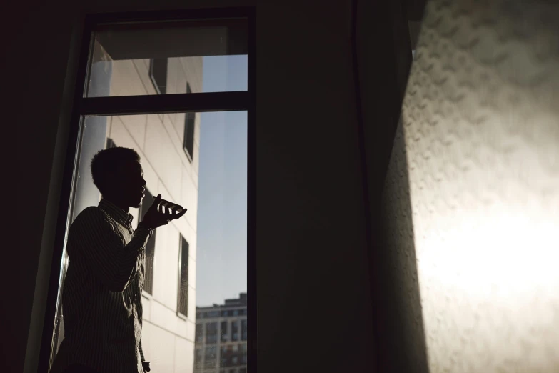 a man holding a camera is standing near the window