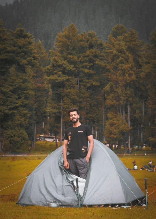 there is a man standing outside of a tent