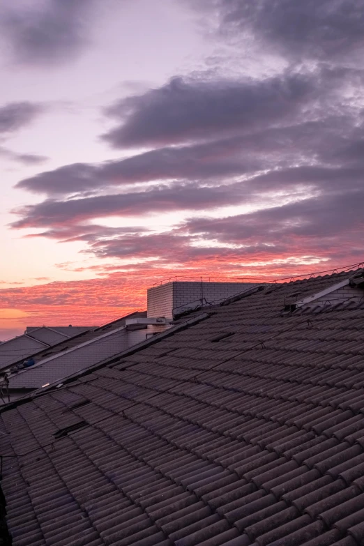 a cloudy sky is pictured above rooftops as the sun sets