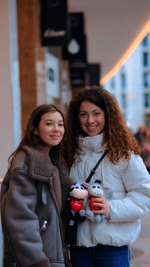 two girls posing for a po with stuffed animals