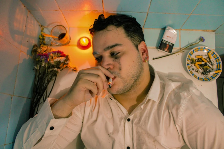 a man sitting on a tiled floor holding a cigarette