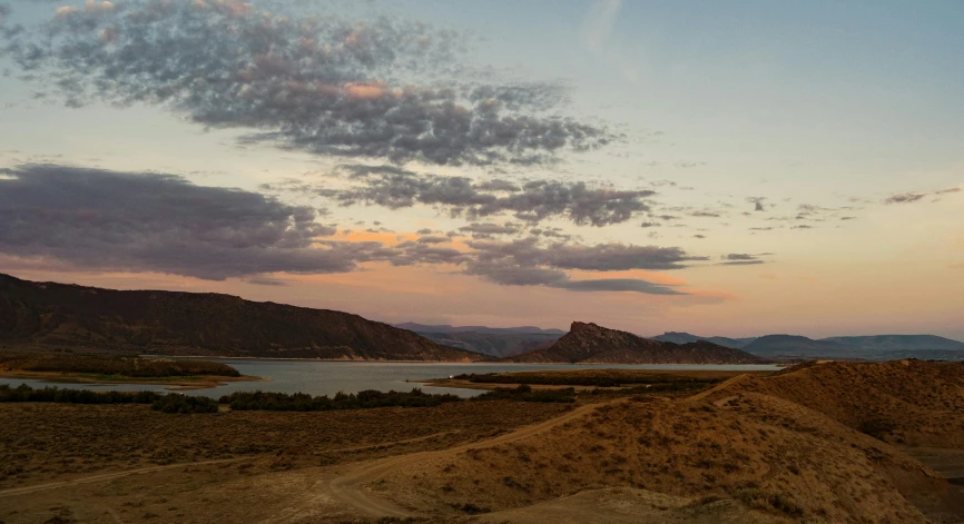 a view of the mountains, water and hills at dusk