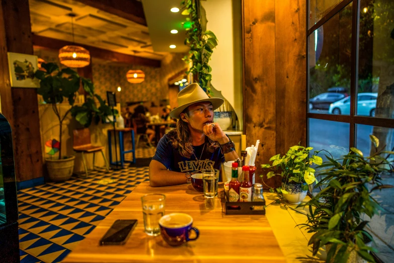 a girl sitting at a table talking on the phone