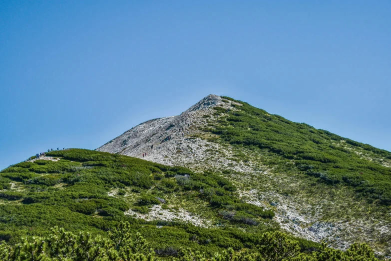 the mountain is rocky, but there is grass growing on top