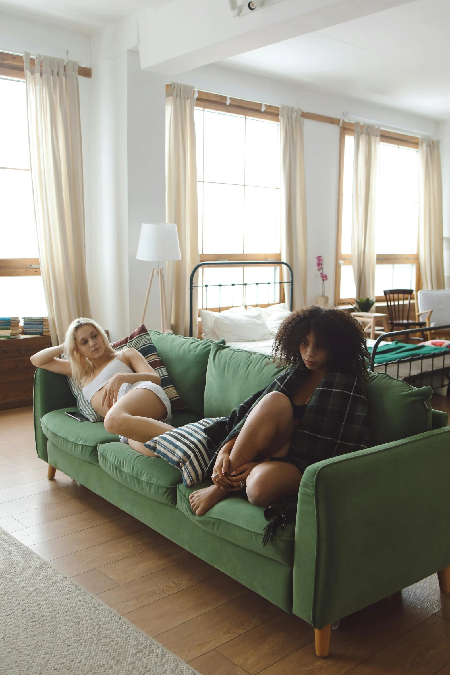 two women sit on a green sofa in a large living room