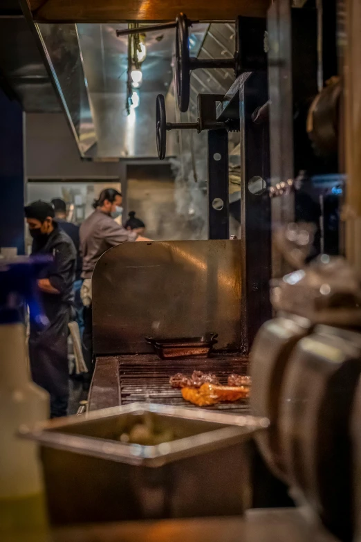 some people standing around a large grill grill