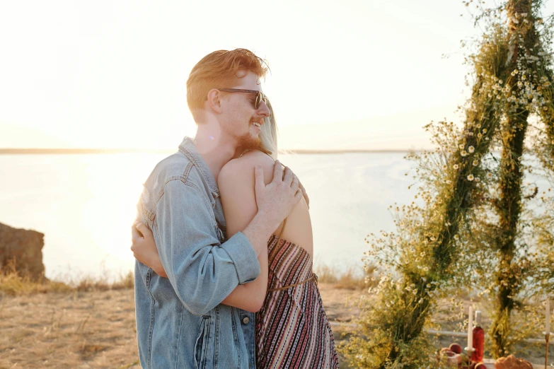 a man and woman hug while standing next to water