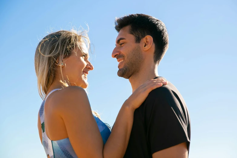 a man and woman standing together with the background of the sky